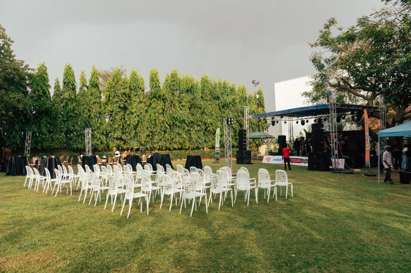 Rows of chairs on grass facing a small outdoor event stage