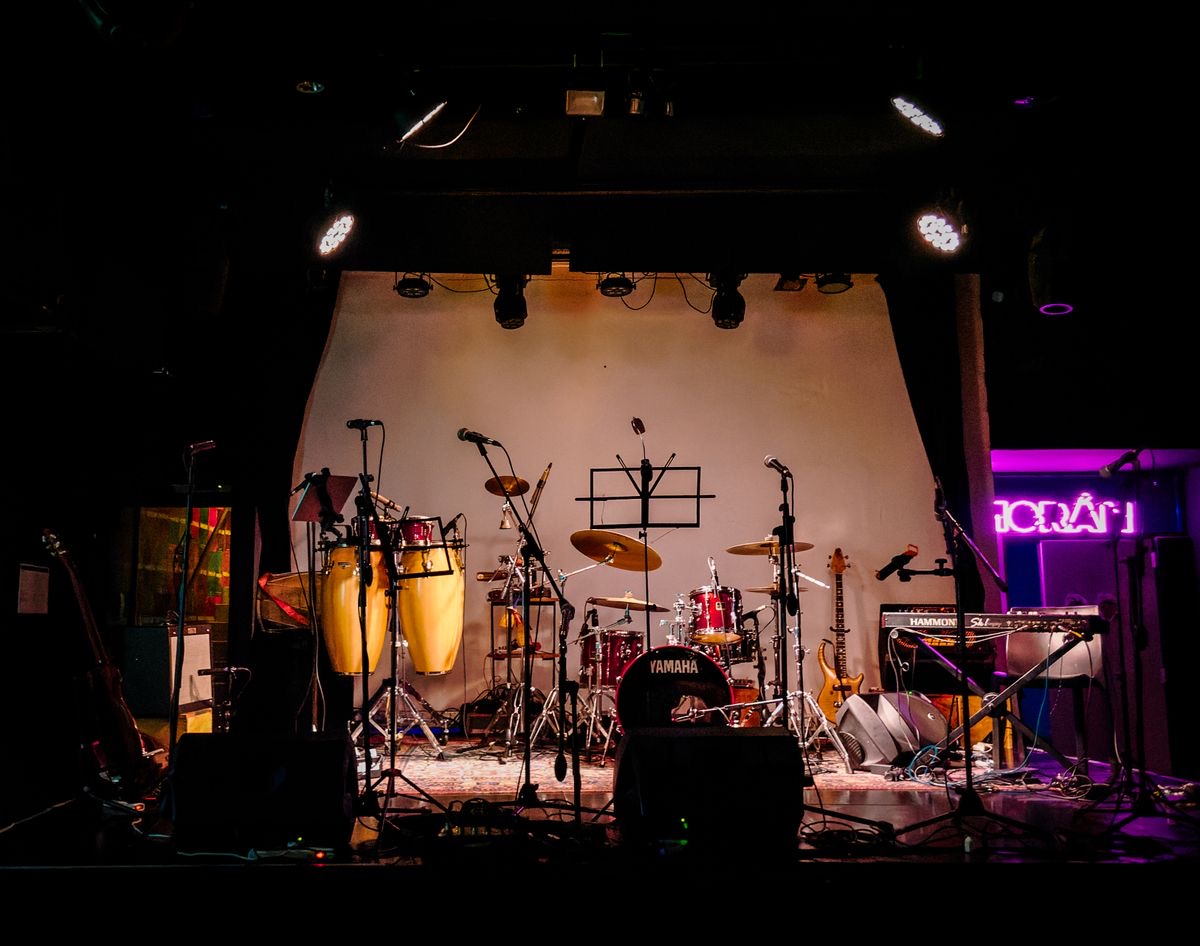 Small music stage with instruments, microphones and a backdrop