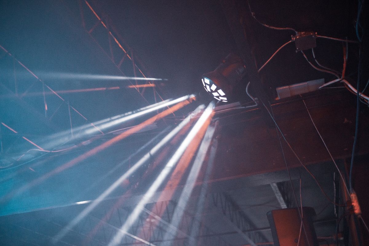 Stage lighting fixture casting beams through a dark event space
